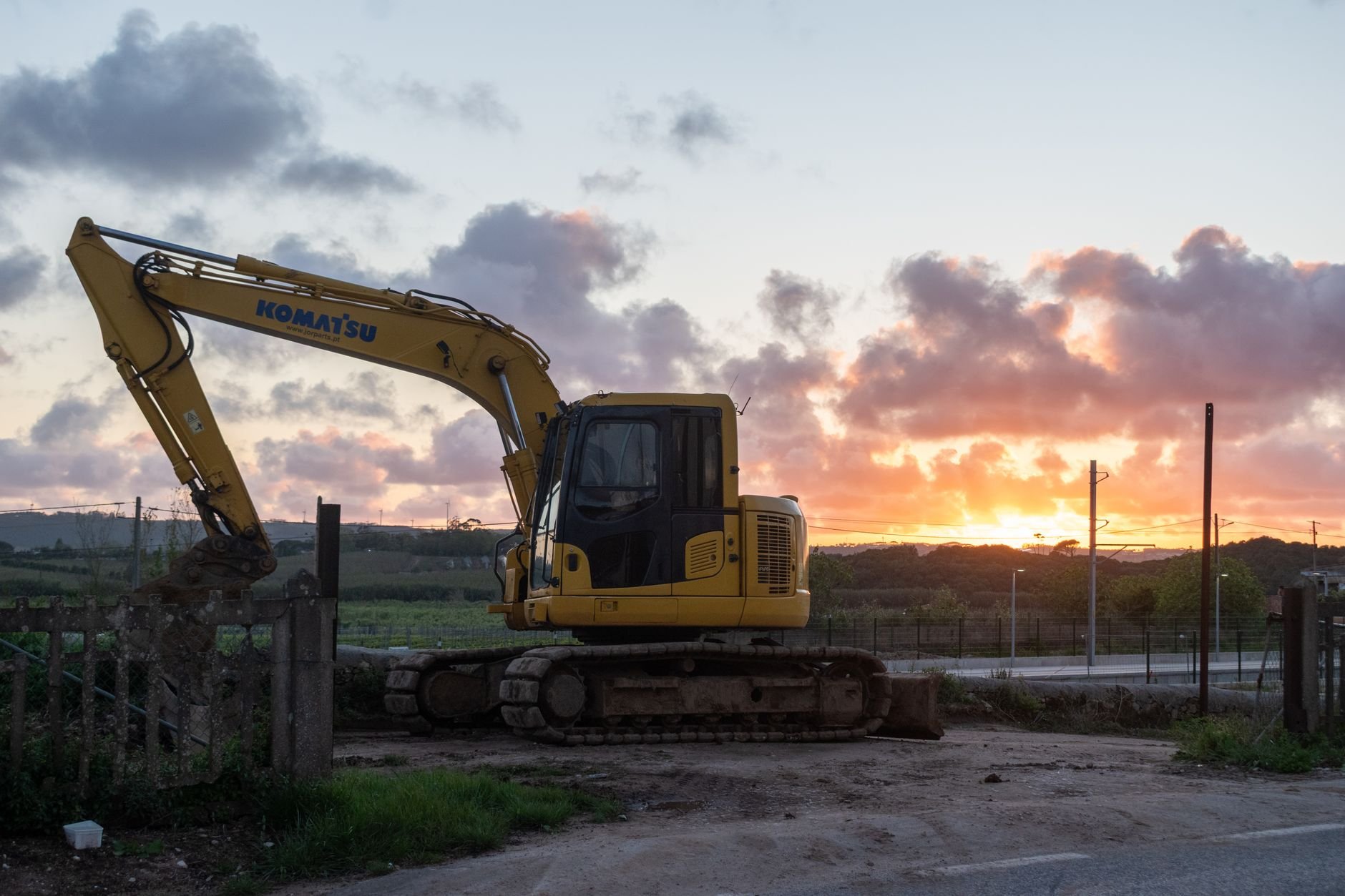 Yellow excavator operating on a construction site at dusk